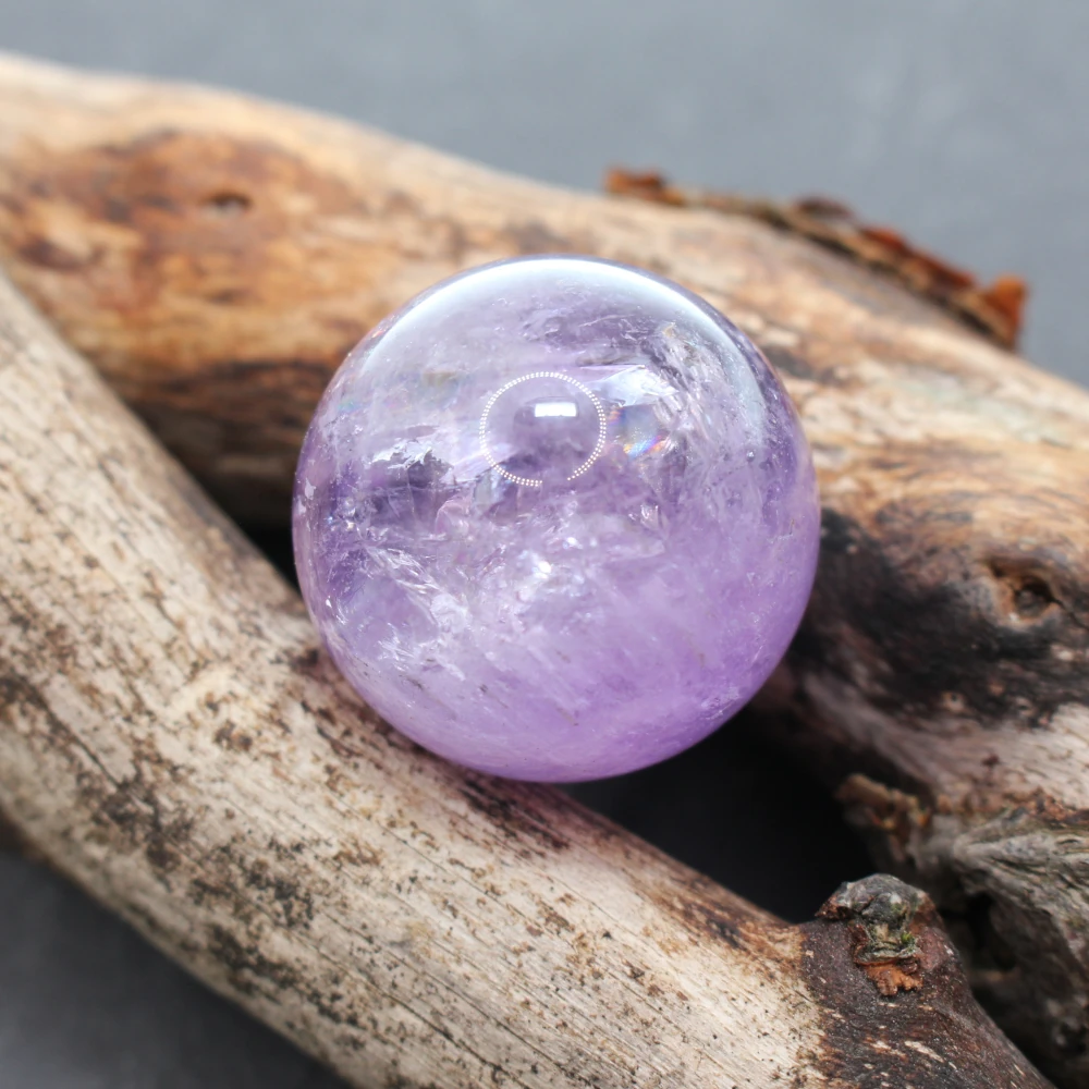 Kugel aus Amethyst liegend auf Holz.