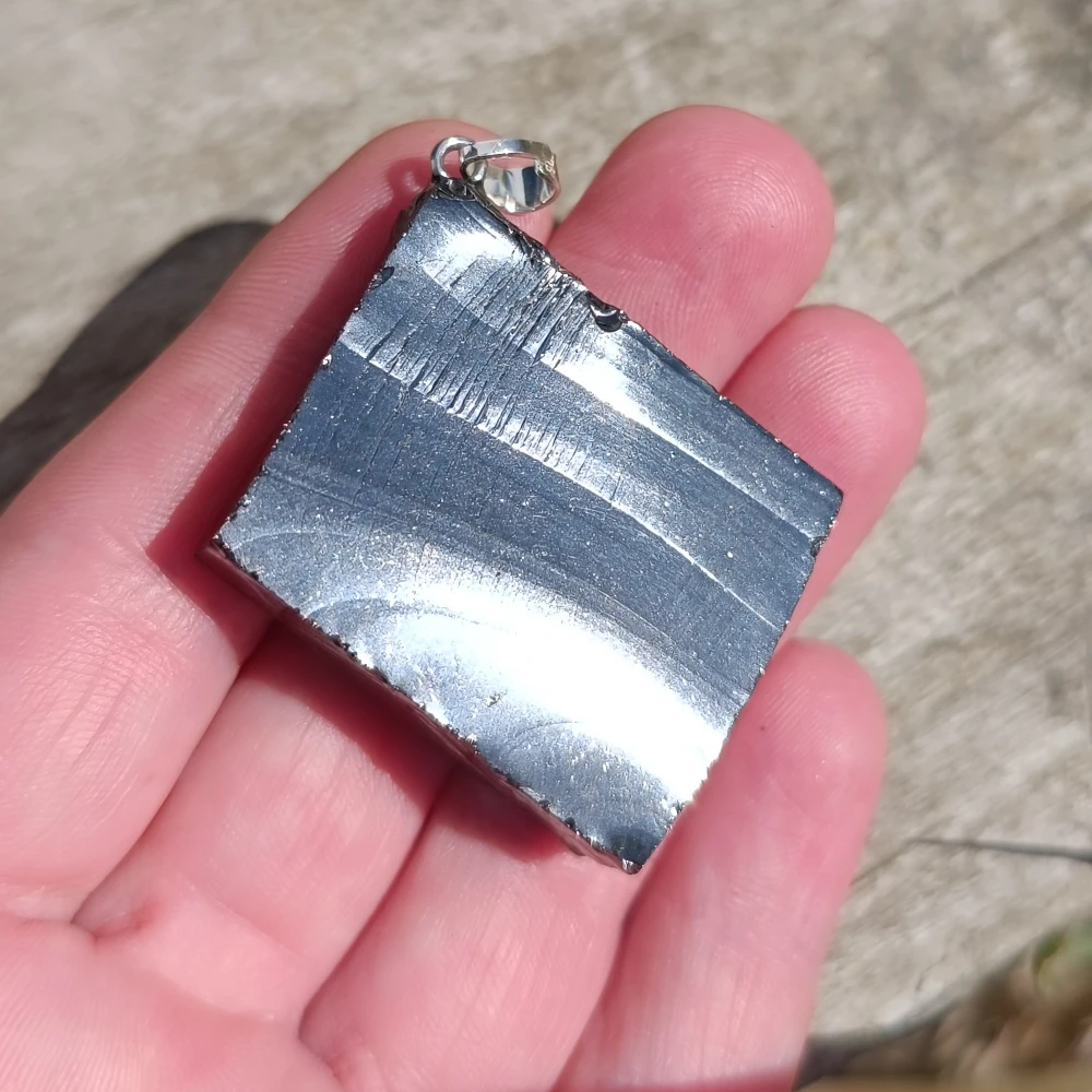Silbriger Elite-Schungit-Anhanenger in der Hand.