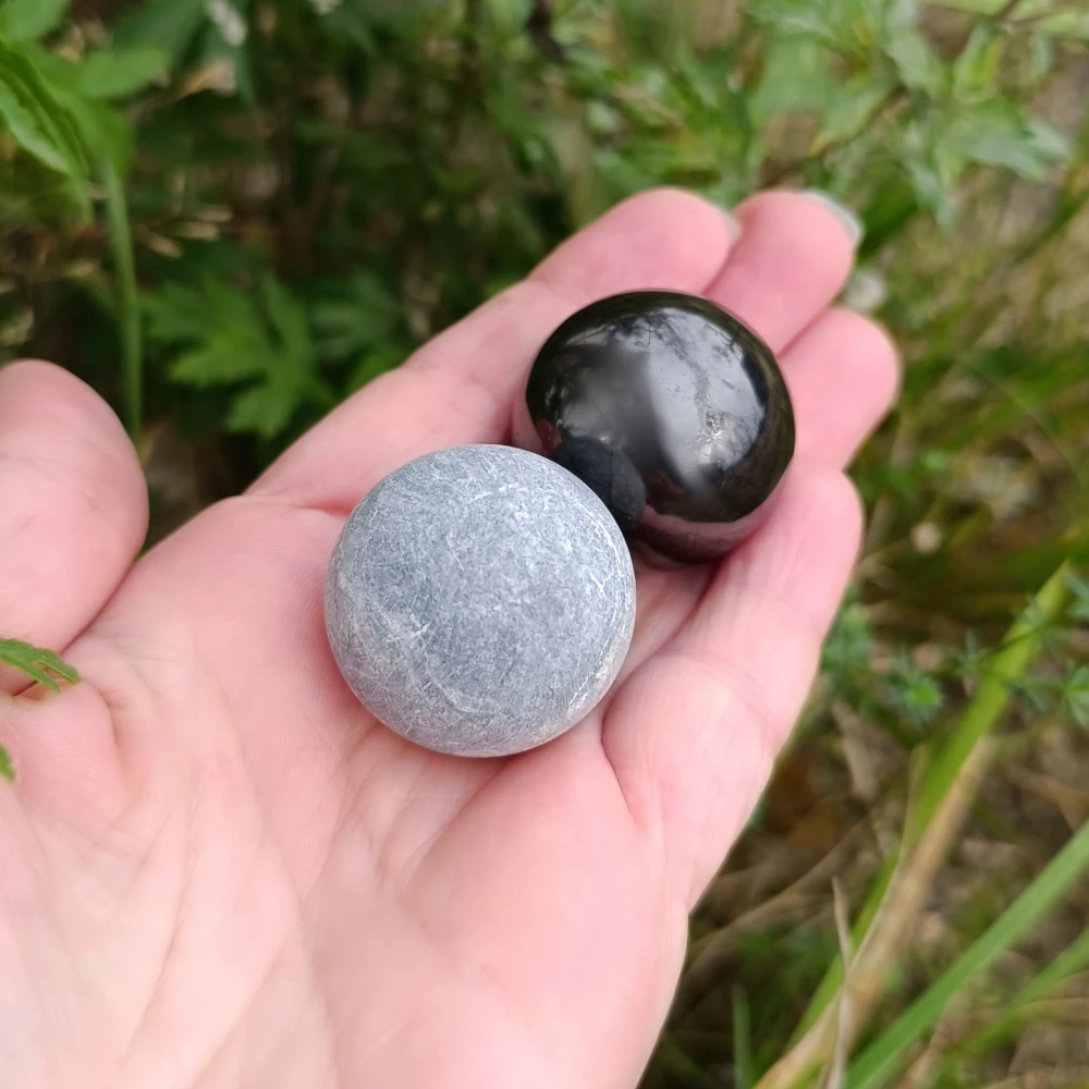 In der Hand haltend zwei Kugeln aus Talkchlorit und Schungit