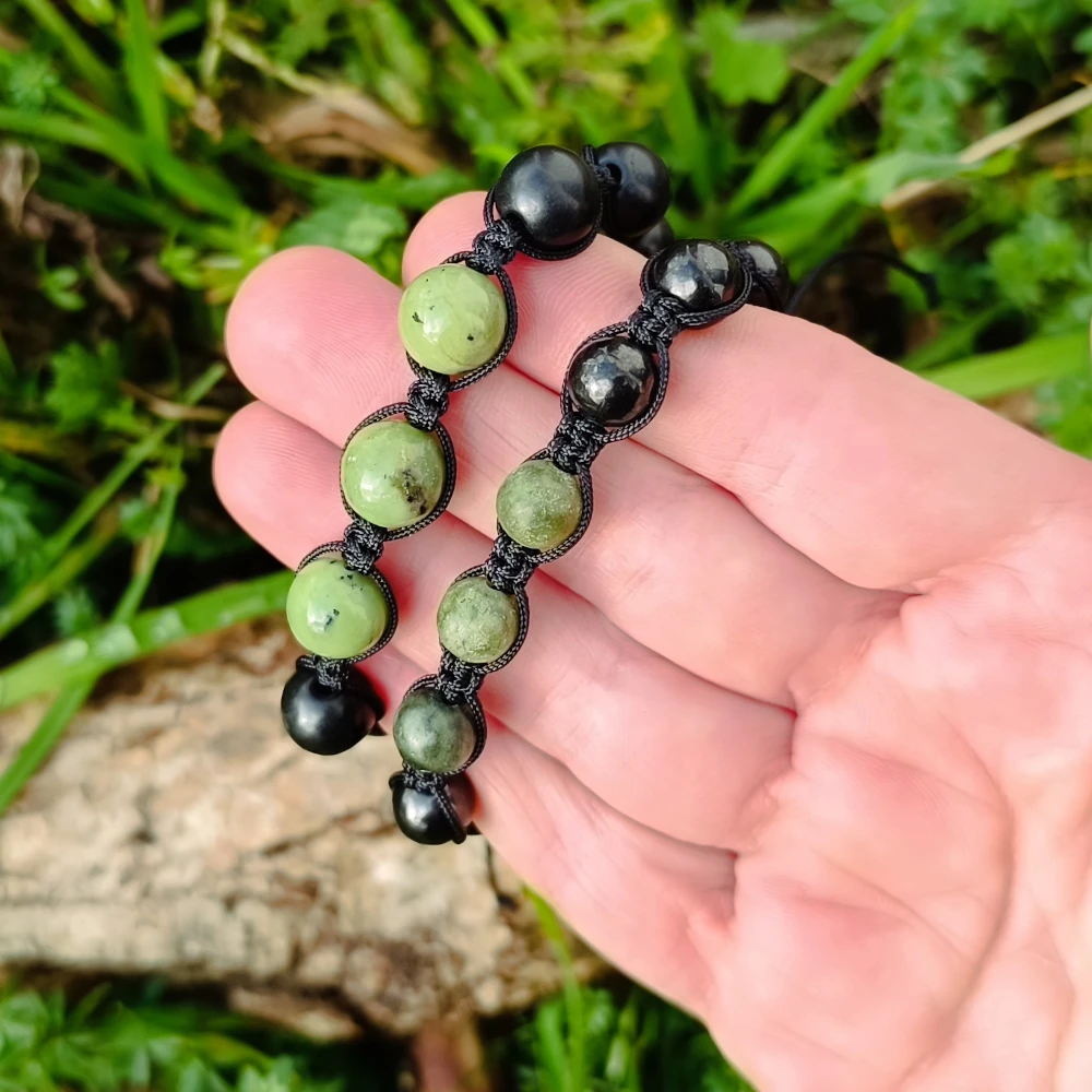 Zwei Kugelarmbaender aus Schungit und Jade in der Hand