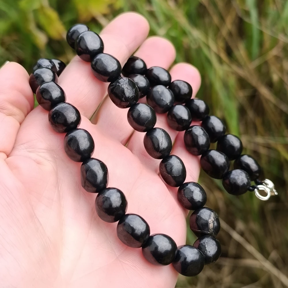 Steinkette aus Schungit mit unregelmaessig geformten Steinchen in der Hand
