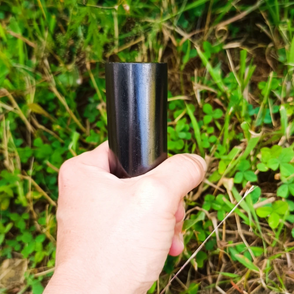 Schungit-Zylinderstab poliert, glänzend schwarz, in der Hand gehalten