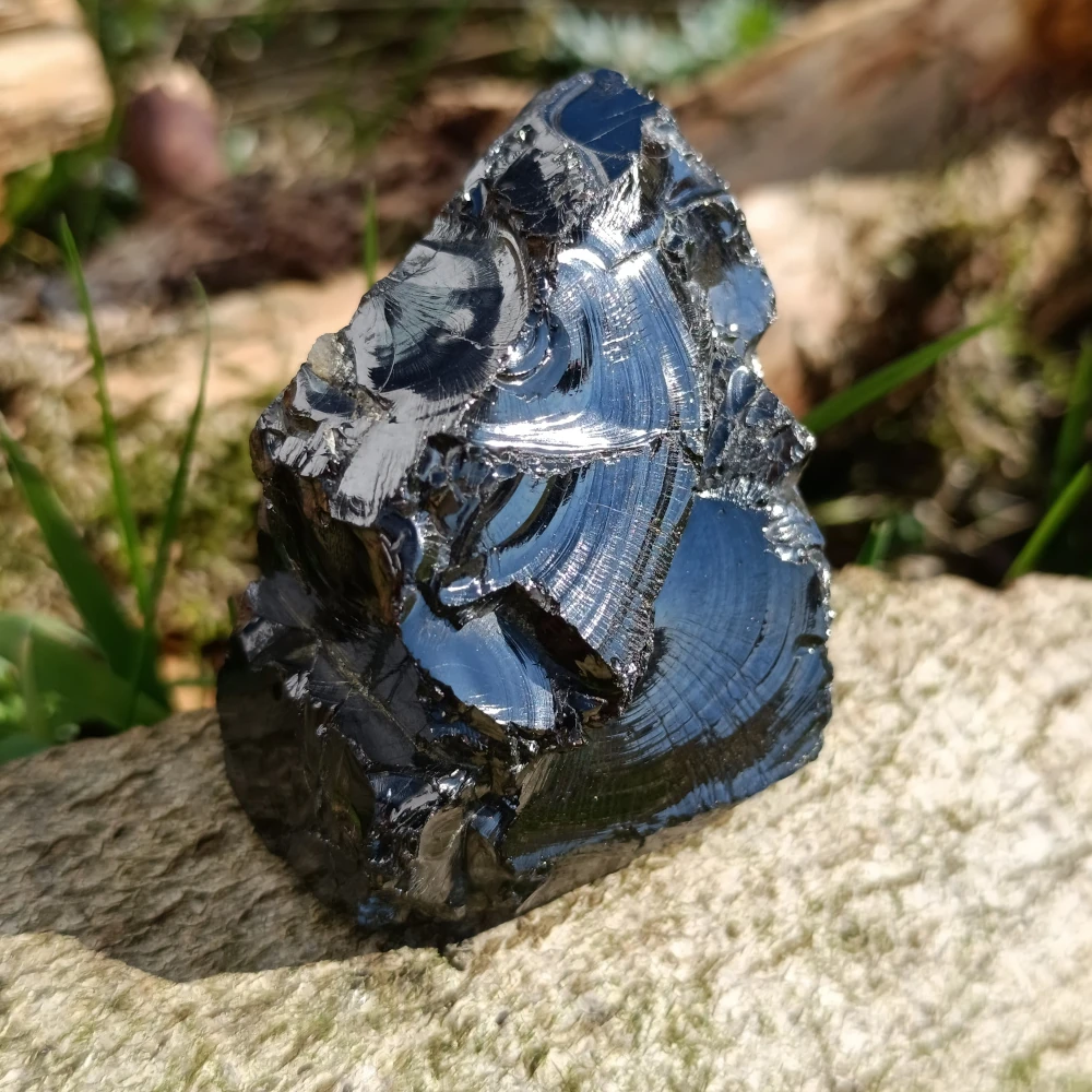 Silbrigschwarz glaenzender Edelschungit auf Holz.