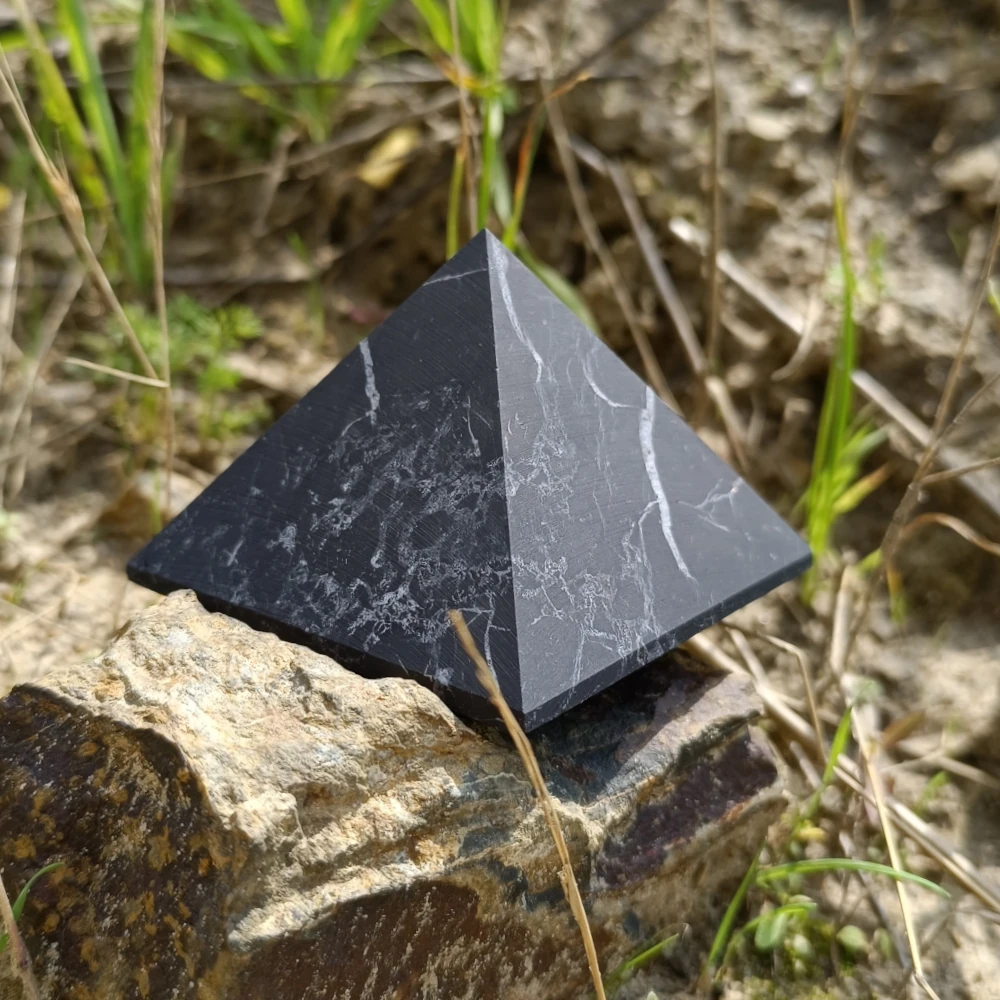 Schungit Pyramide in unpolierter Form auf Stein stehend