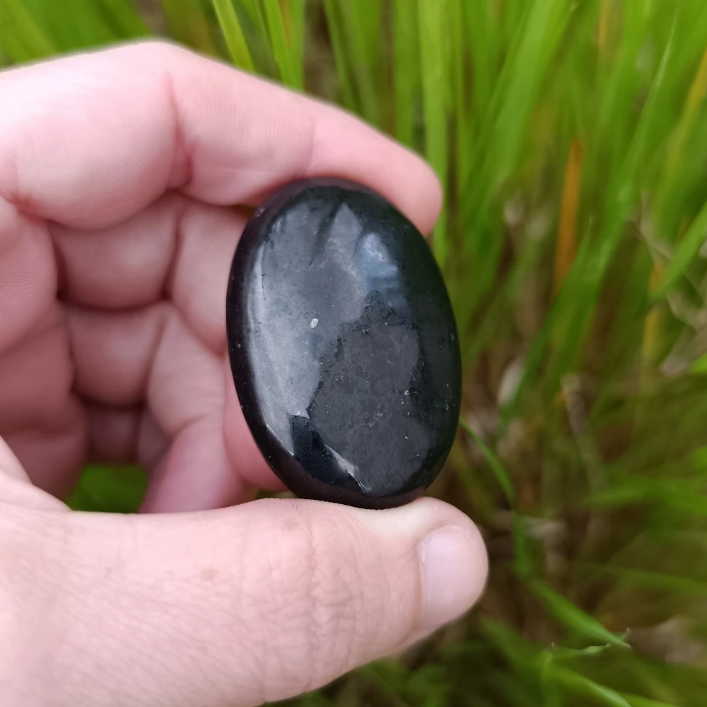 Linsenstein aus Schungit in der Hand