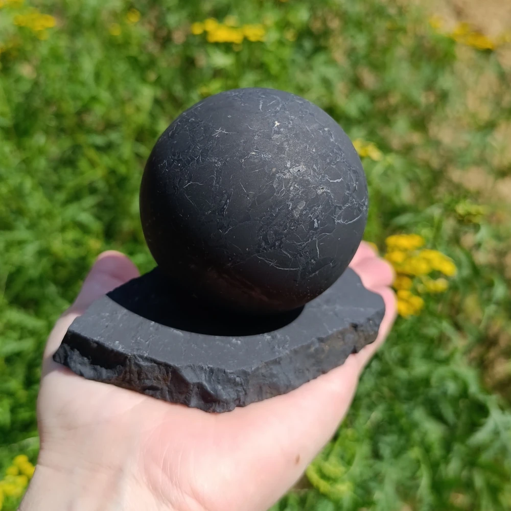 Schungitkugel auf einem Schungit Kugelhalter in der Hand