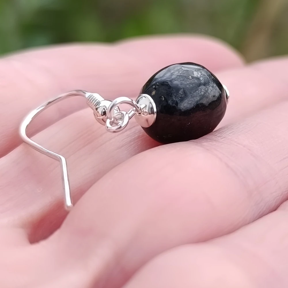 Trommelsteinohrring aus Schungit in der Hand liegend