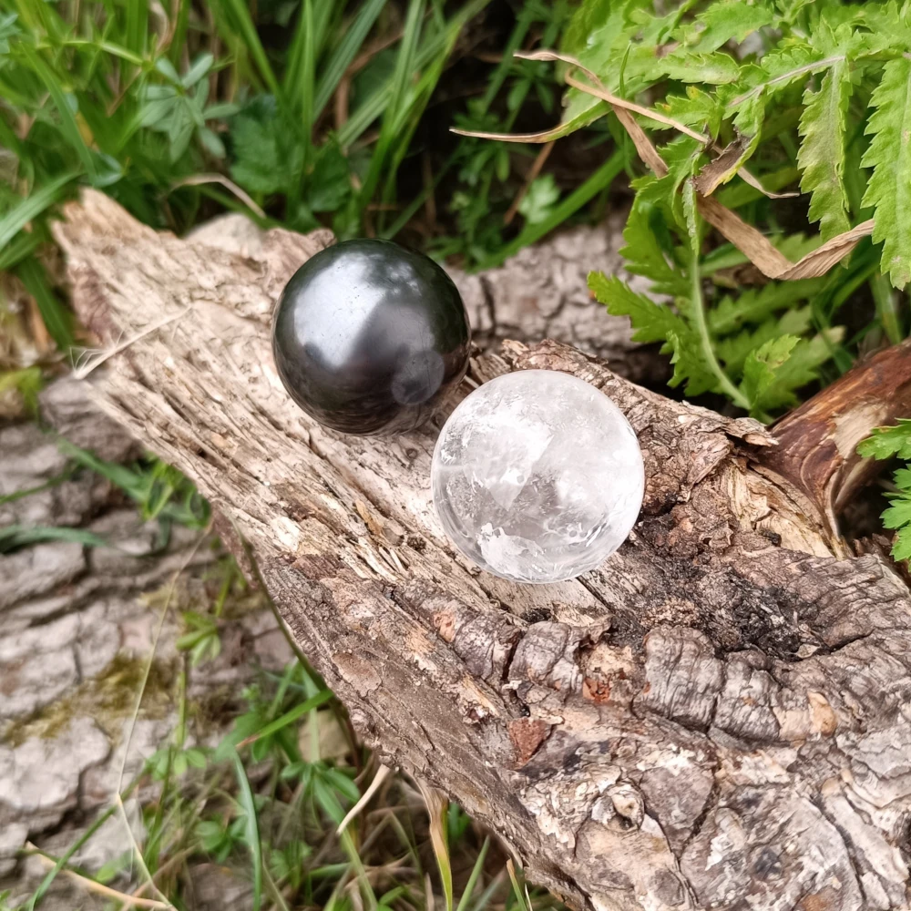 Kugeln auf Baumstamm liegend aus Bergkristall und Schungit