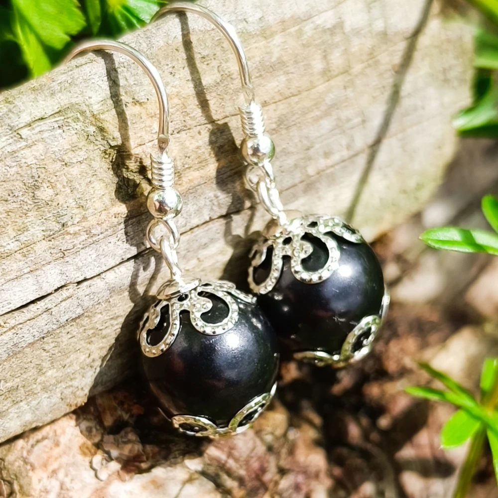 Bei Sonnenschein abgebildete Kugelohrringe aus Schungit mit Blumen Kaschierperlen