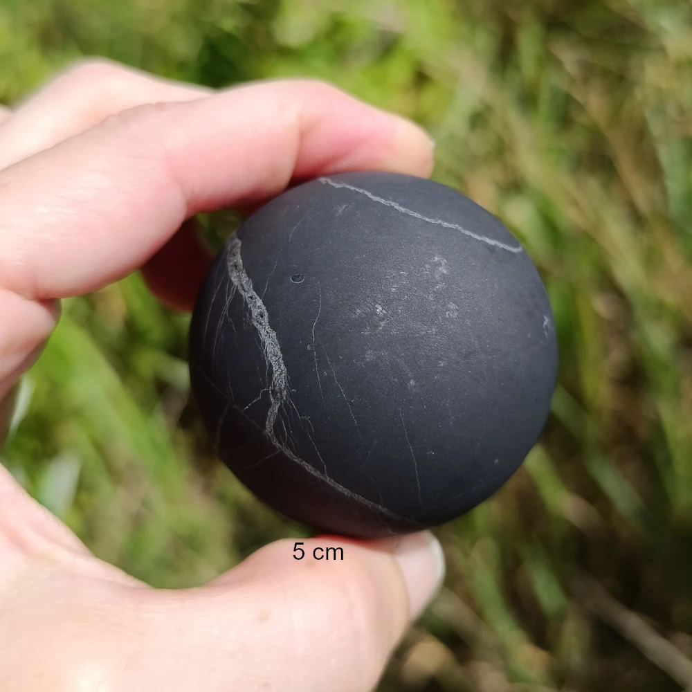 Fuenf Zentimeter groesse Schungitkugel in der Hand
