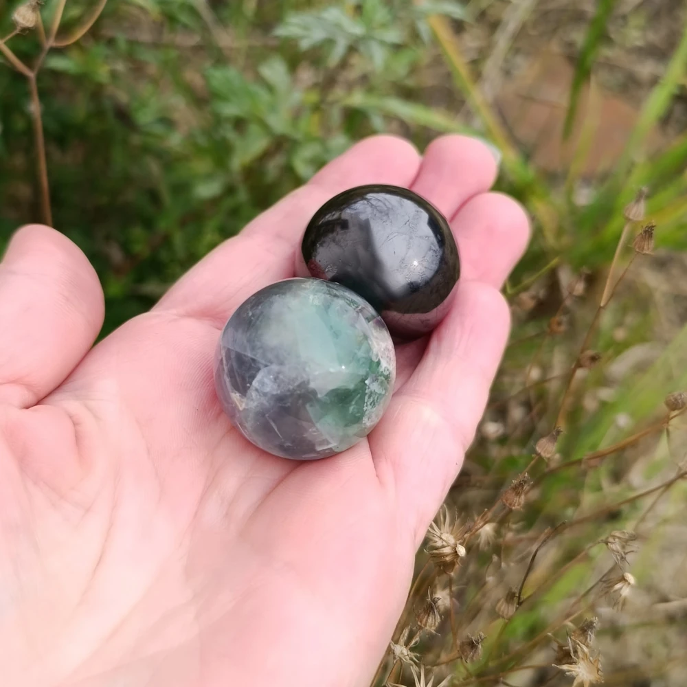 In der Hand liegende Schungit und Fluorit Kugeln