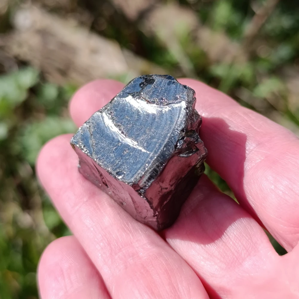 Kleiner Edel-Schungit-Stein auf einer Hand liegend.