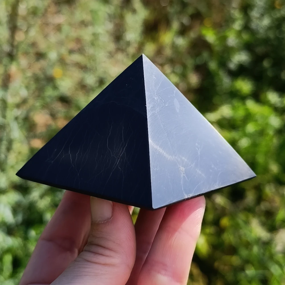 Polierte Schungit Pyramide auf den Fingern