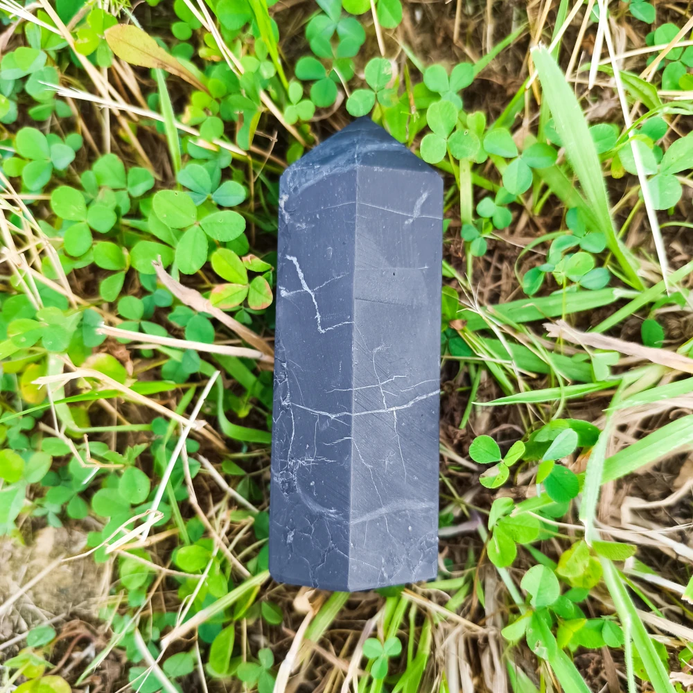 Schungit-Obelisk, unpoliert, dunkelgrau, auf Naturuntergrund liegend