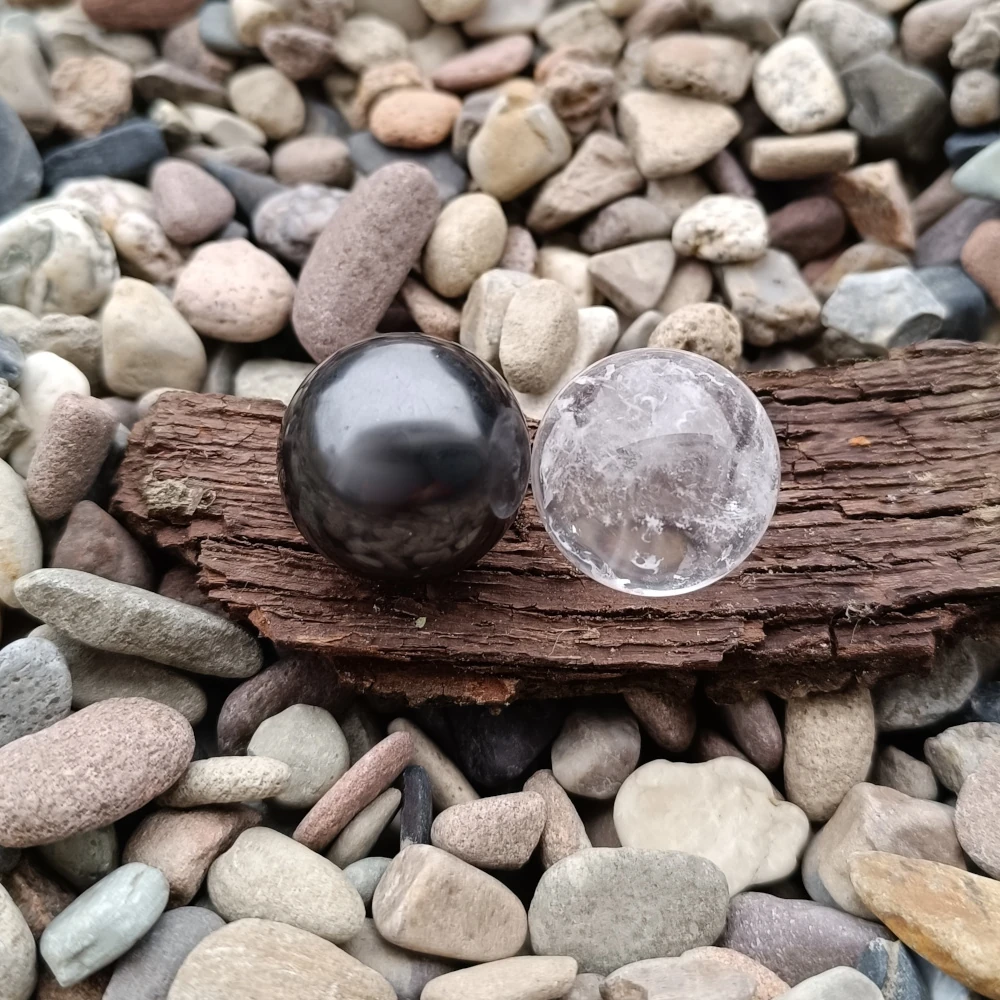 Kugeln aus Schungit und Bergkristall auf Baumrinde liegend