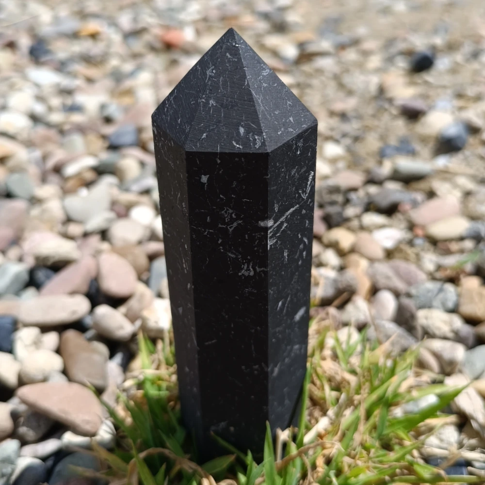 Schungit-Obelisk, unpoliert, auf Kieselsteinen stehend