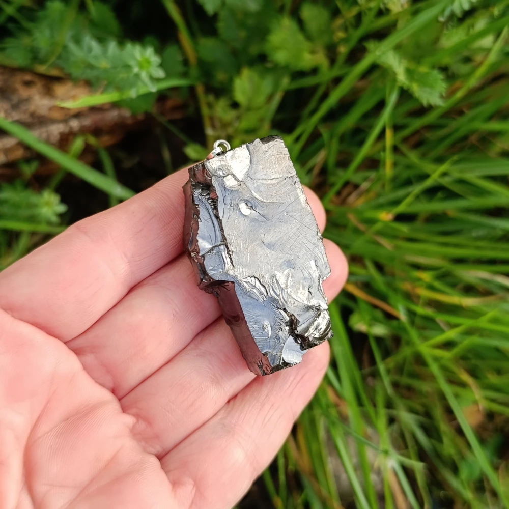 Freiförmiger Edelschungit Anhänger in der Hand