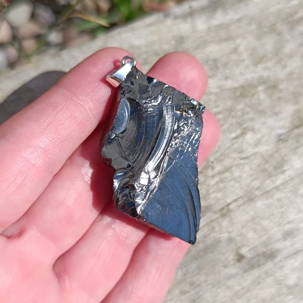 Freiförmiger Edelschungit Anhänger in der Hand