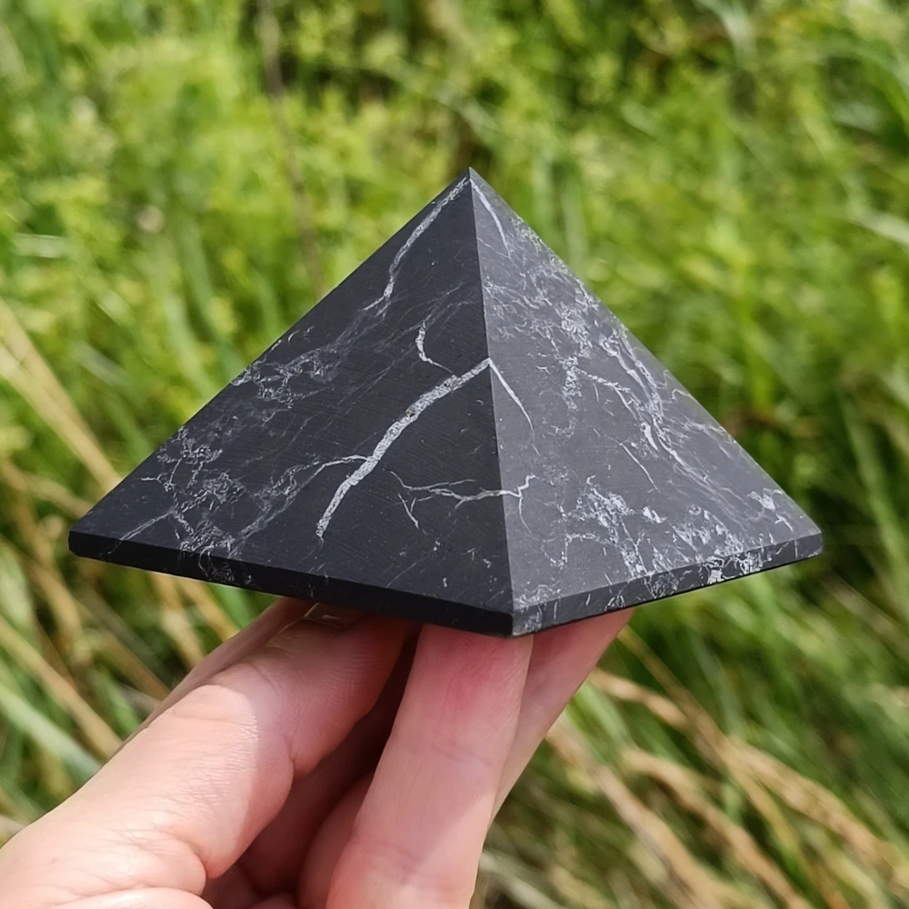 Unpolierte Pyramide aus Schungit in der Hand