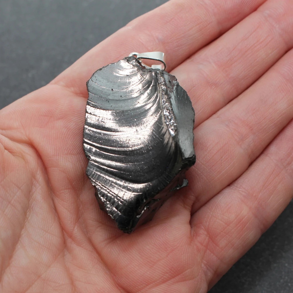 Halsanhänger aus Edelschungit in der Hand