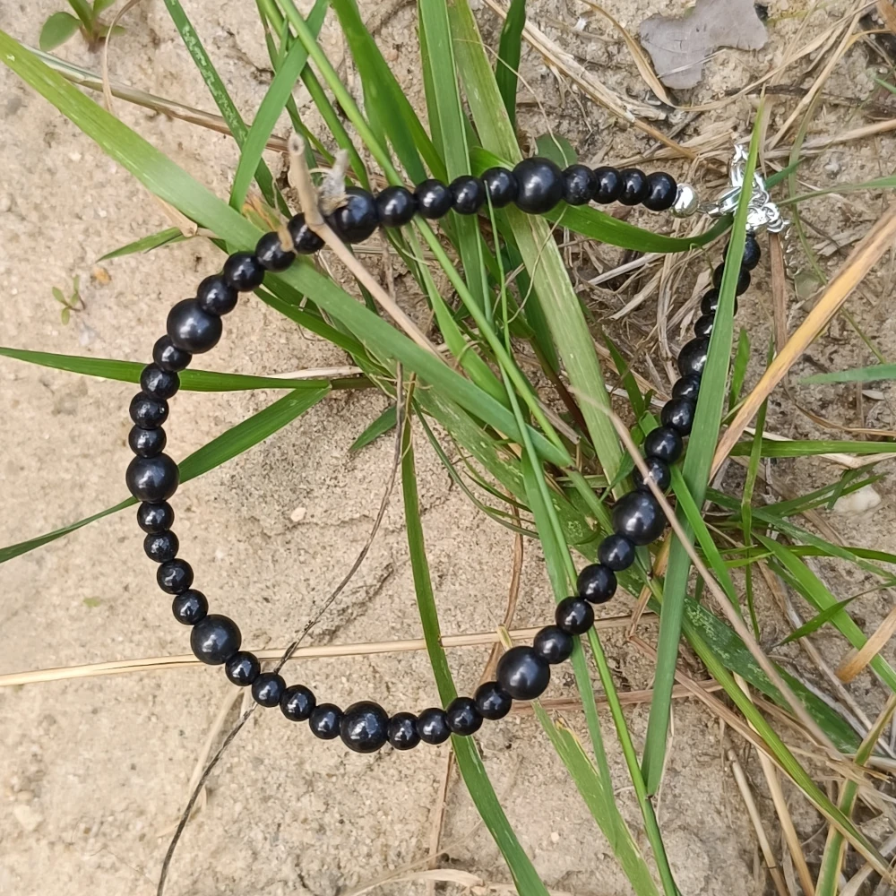 Schungit Fusskugelkette auf Sand liegend