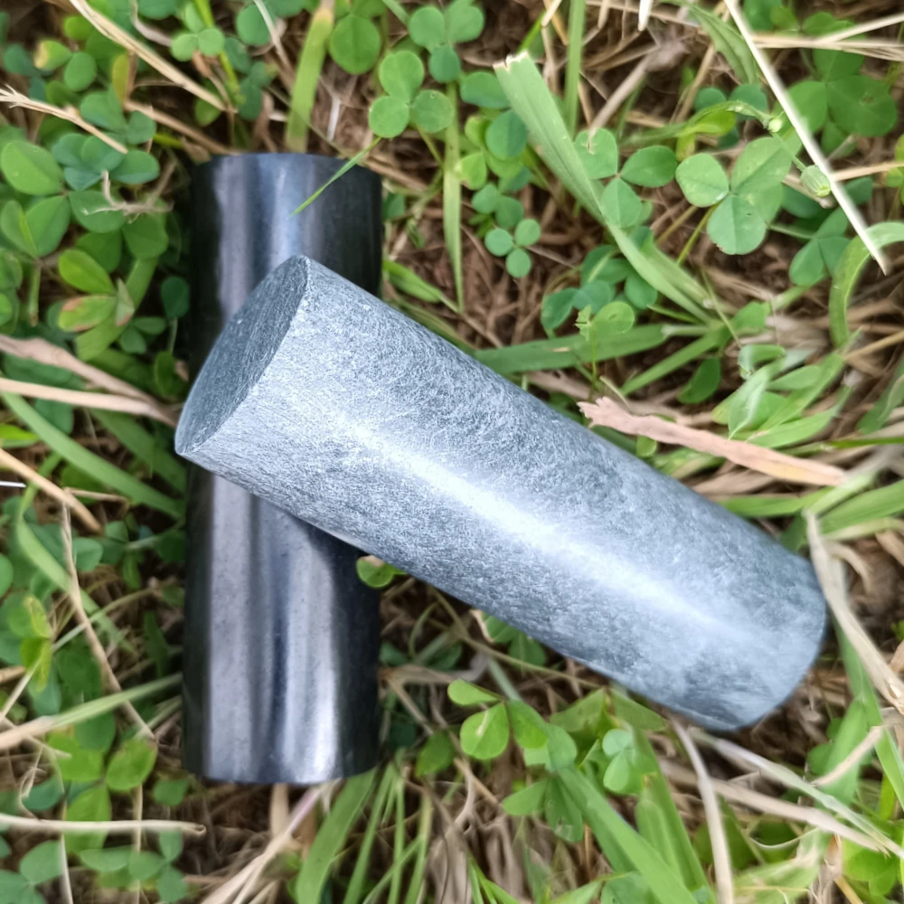 Schungit-Zylinder poliert, schwarzer und grauer Zylinder, in der Hand