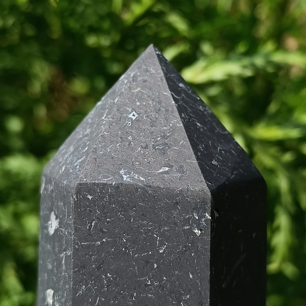 Schungit-Obelisk, unpoliert, dunkelgrau, auf Naturuntergrund stehend