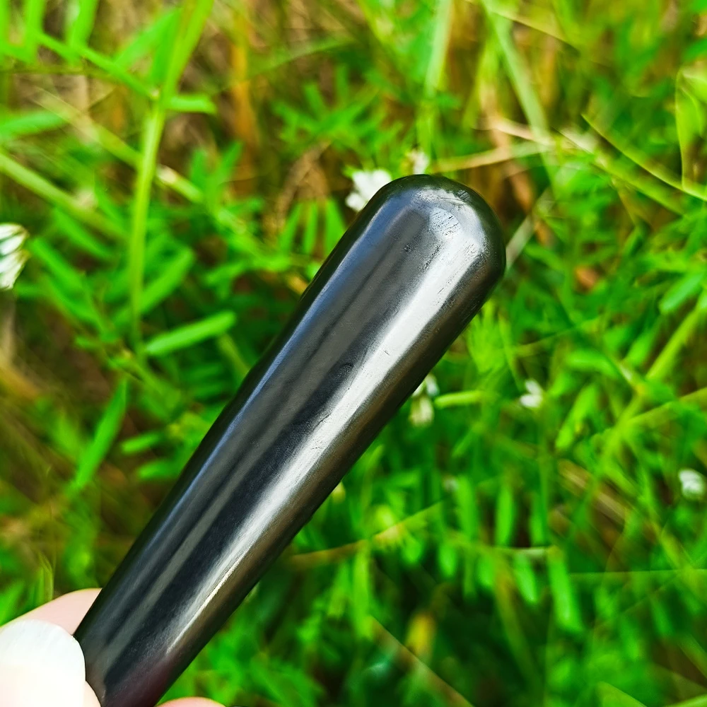 Schungit-Massagestift in der Hand, poliert