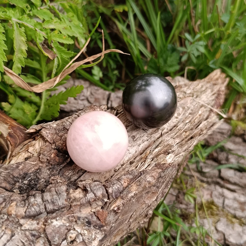 Auf Holz liegend Kugeln aus Rosenquarz und Schungit