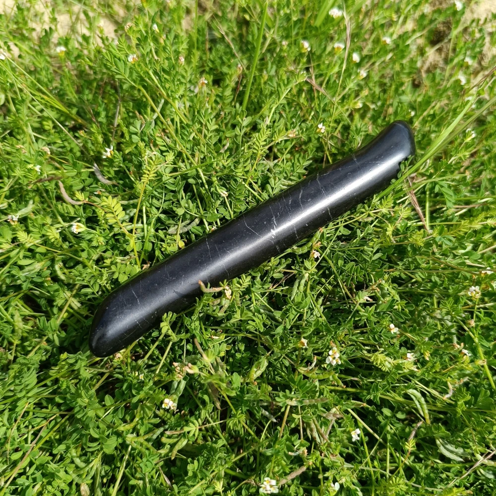 Schungit-Massagestift, poliert, auf Naturuntergrund