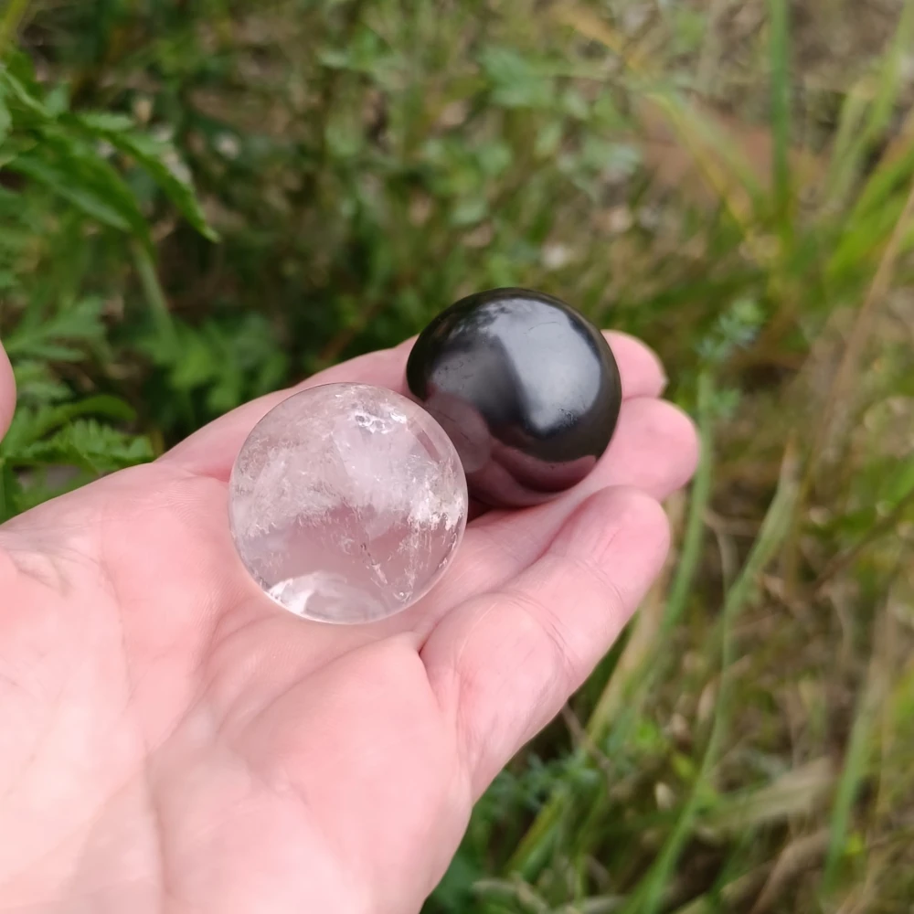 In der Hand liegende Kugeln aus Bergkristall und Schungit