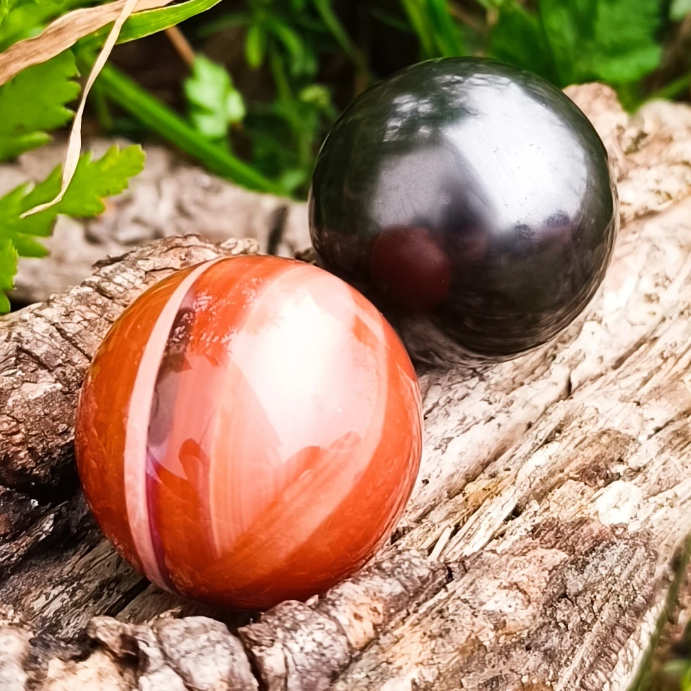 Auf Holz liegende Kugeln aus Schungit und Karneol