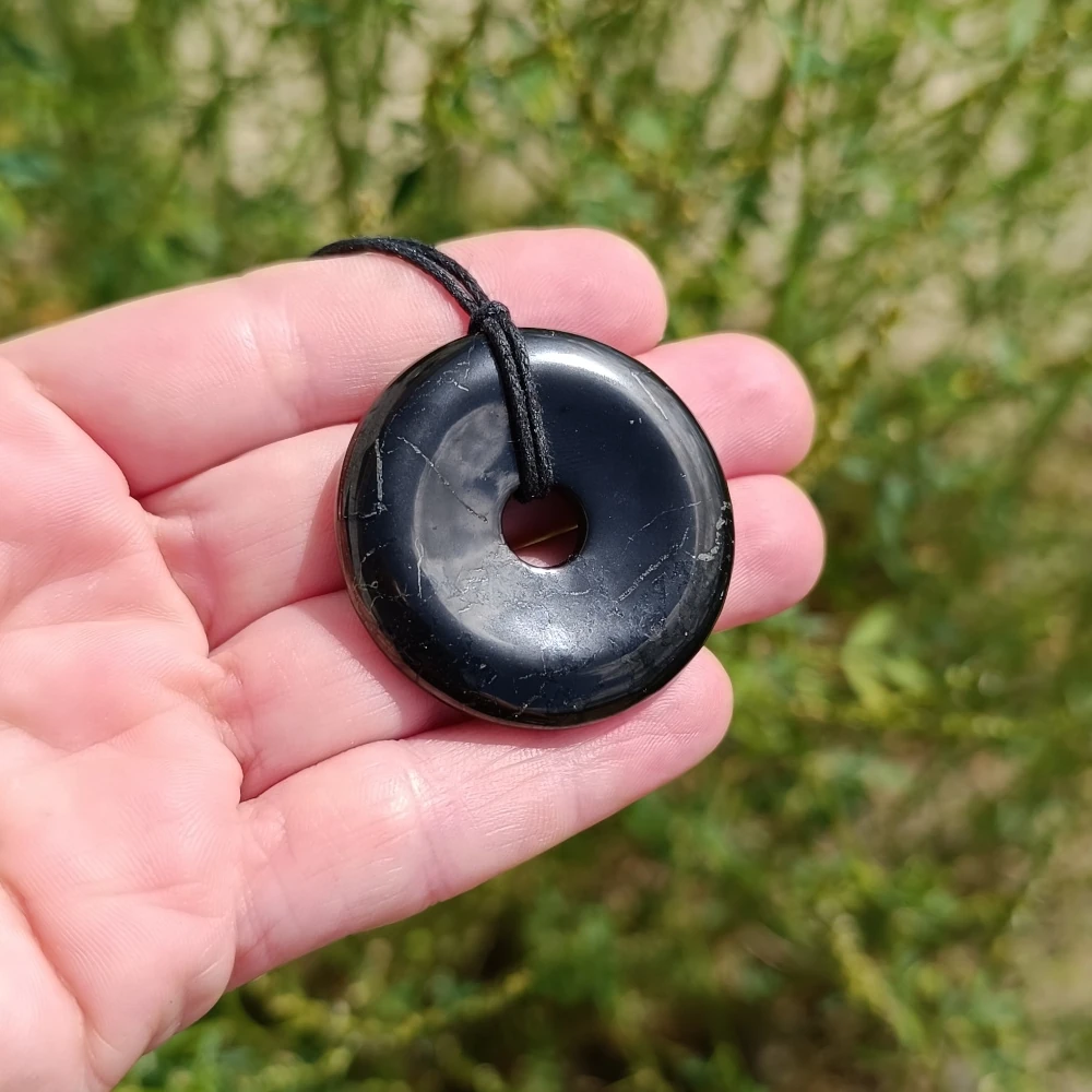Donut aus Schungit mit Baumwollschnur in der Hand