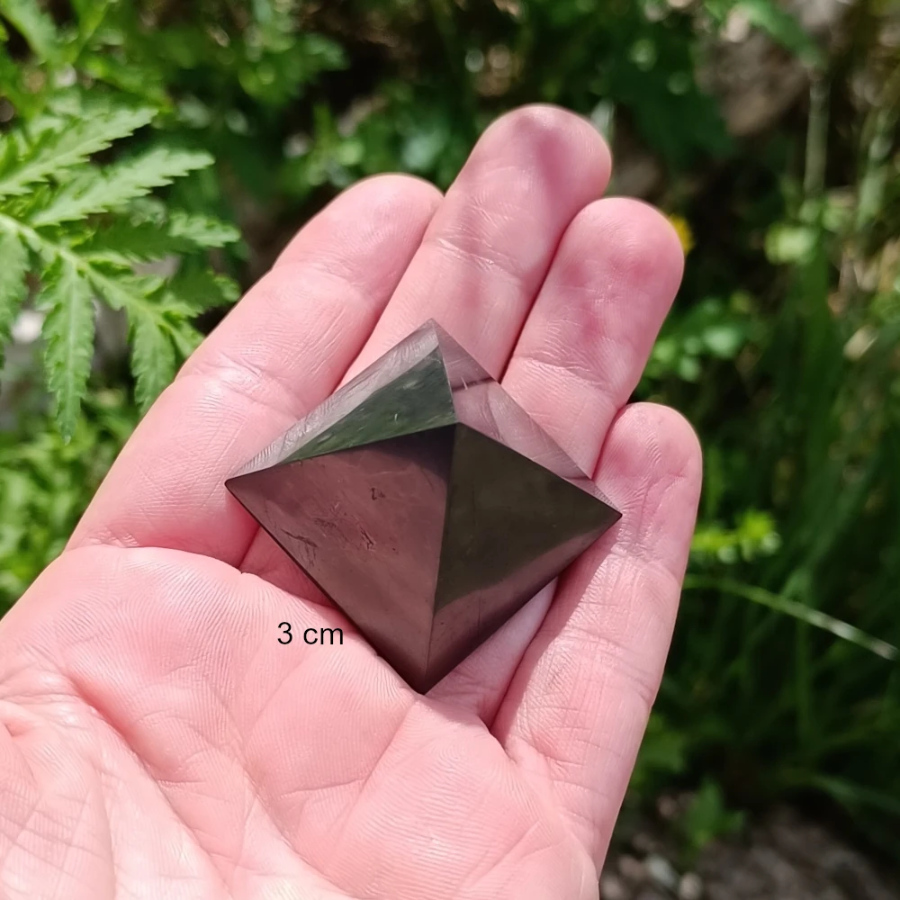 Kleine polierte Schungit Pyramide in der Handinnenflaeche