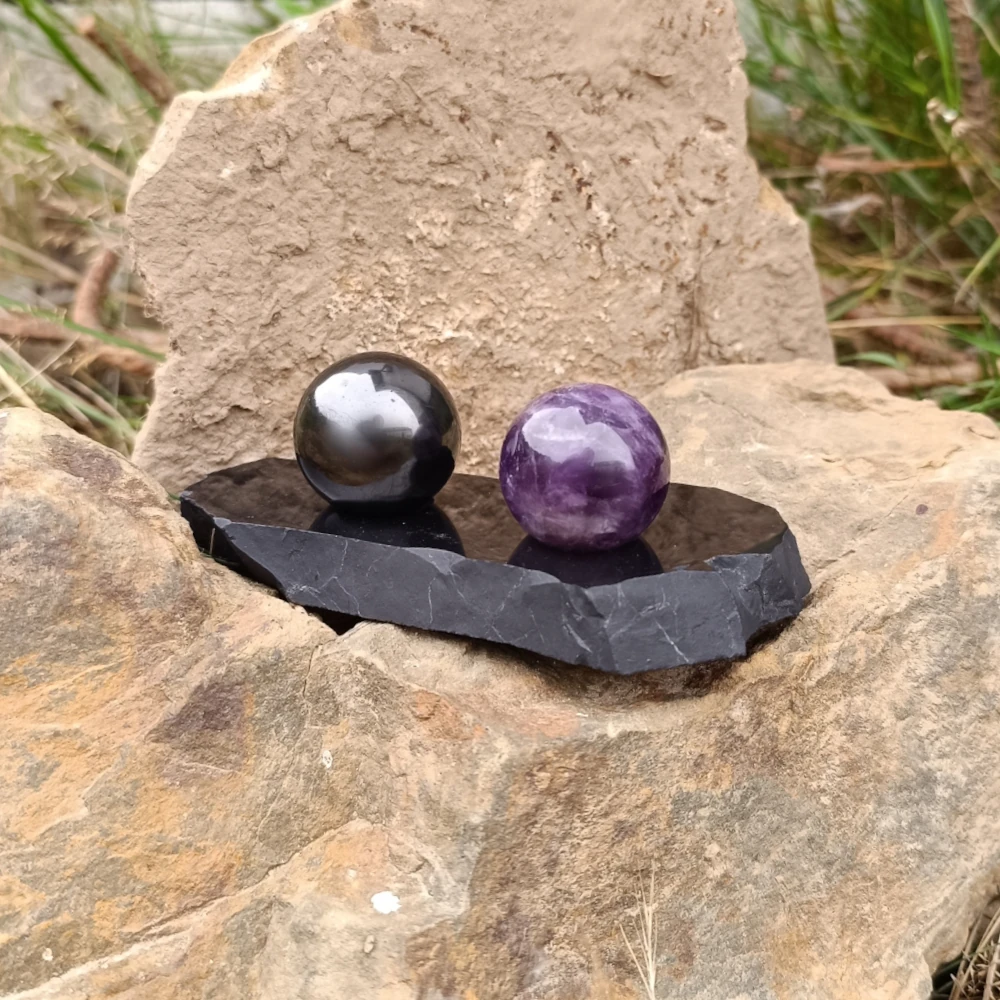 Harmonisierende Kugeln aus Amethyst und Schungit auf einem Schungitkugelhalter