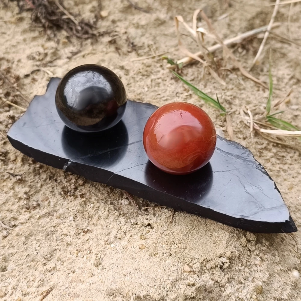Kugelset aus Schungit und Karneol auf einem Schungituntersetzer
