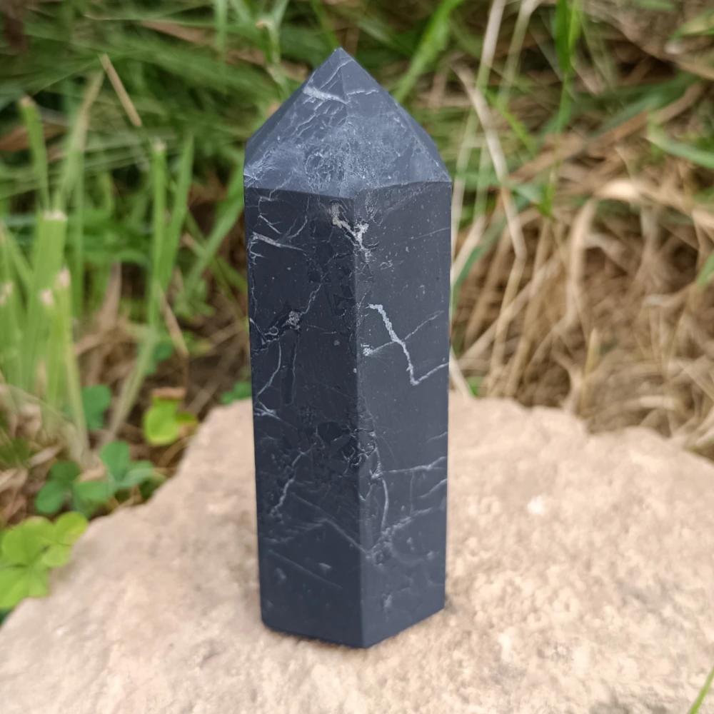 Schungit-Obelisk unpoliert, matt dunkelgrau, auf Sanduntergrund stehend