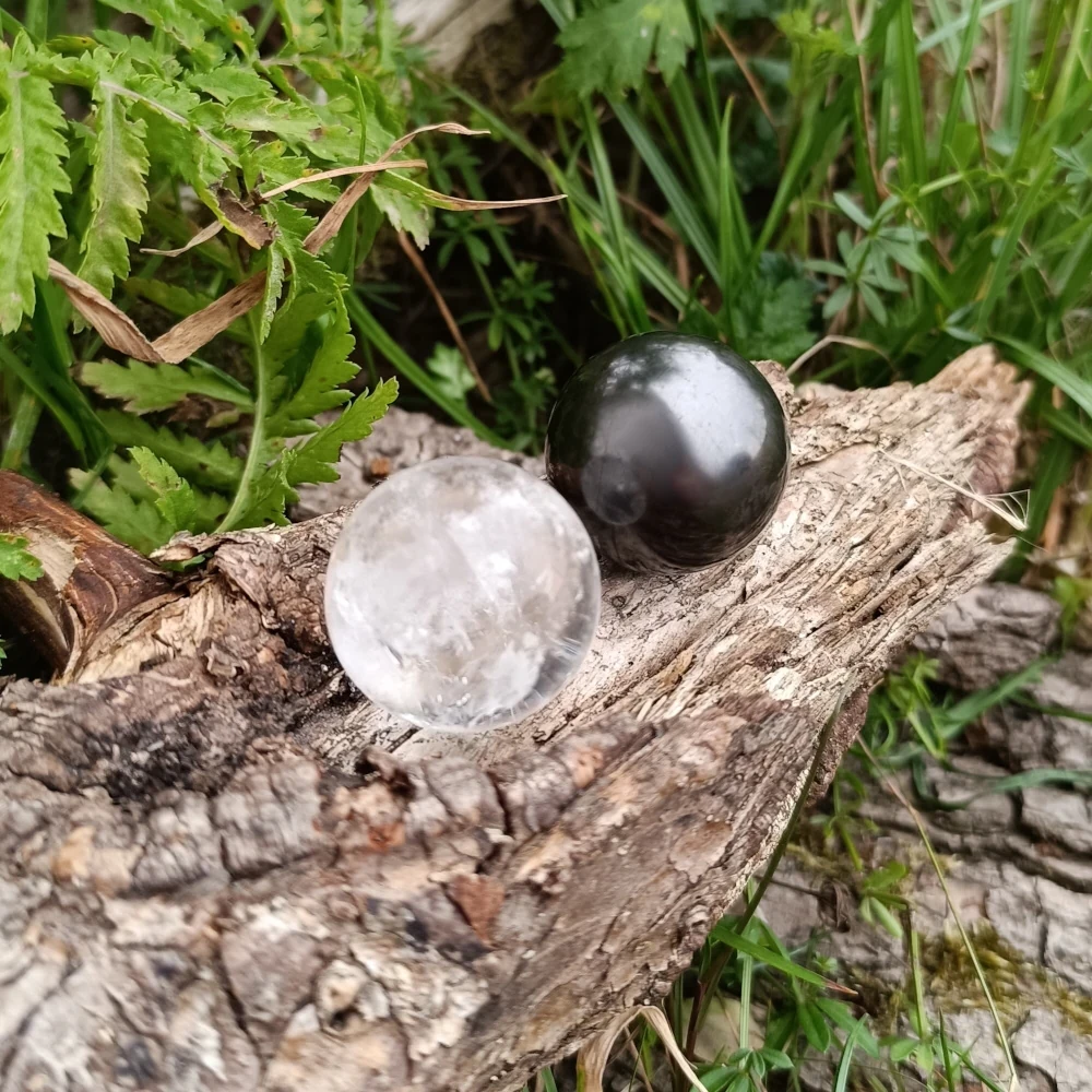 Auf Holz präsentierte Kugel aus Bergkristall und Schungit
