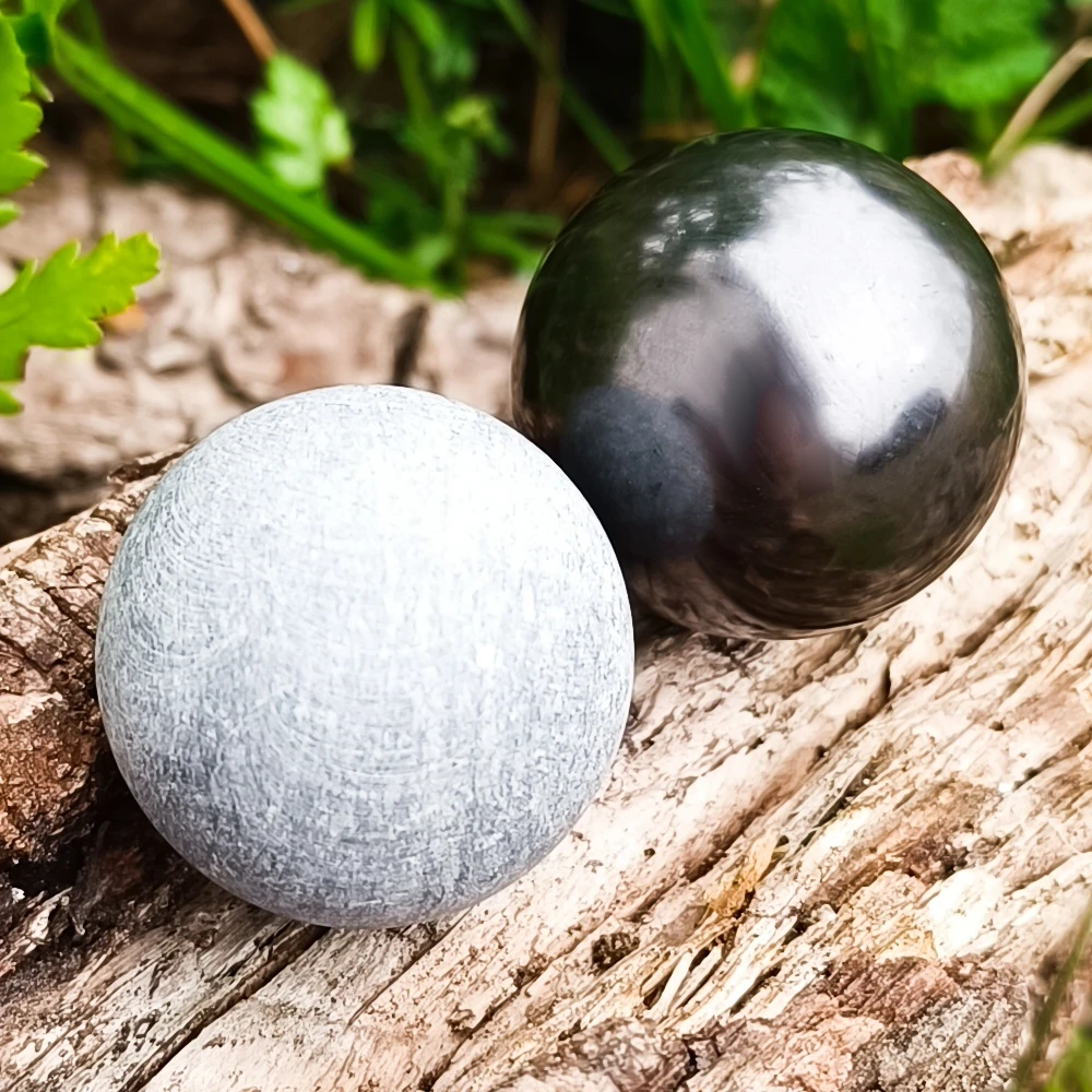 Helle Stpecksteinkugel und schwarze Schungit Kugel auf Holz